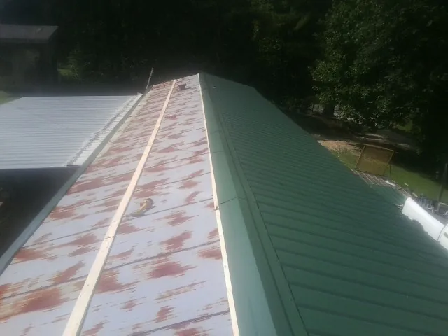 Old rusted panels beside newly installed green metal roofing — Wind Damage Roof Repair by Roofing Brothers in Omaha