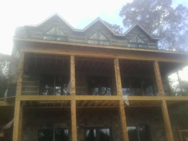 Dormers and porch framing on a large log home under construction — Roof Coating work by our crew in Omaha
